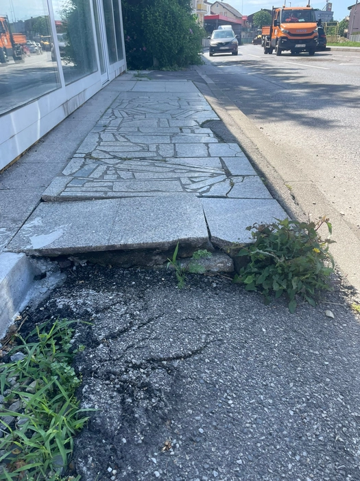 Uneven sidewalk with cracks and vegetation (121667)