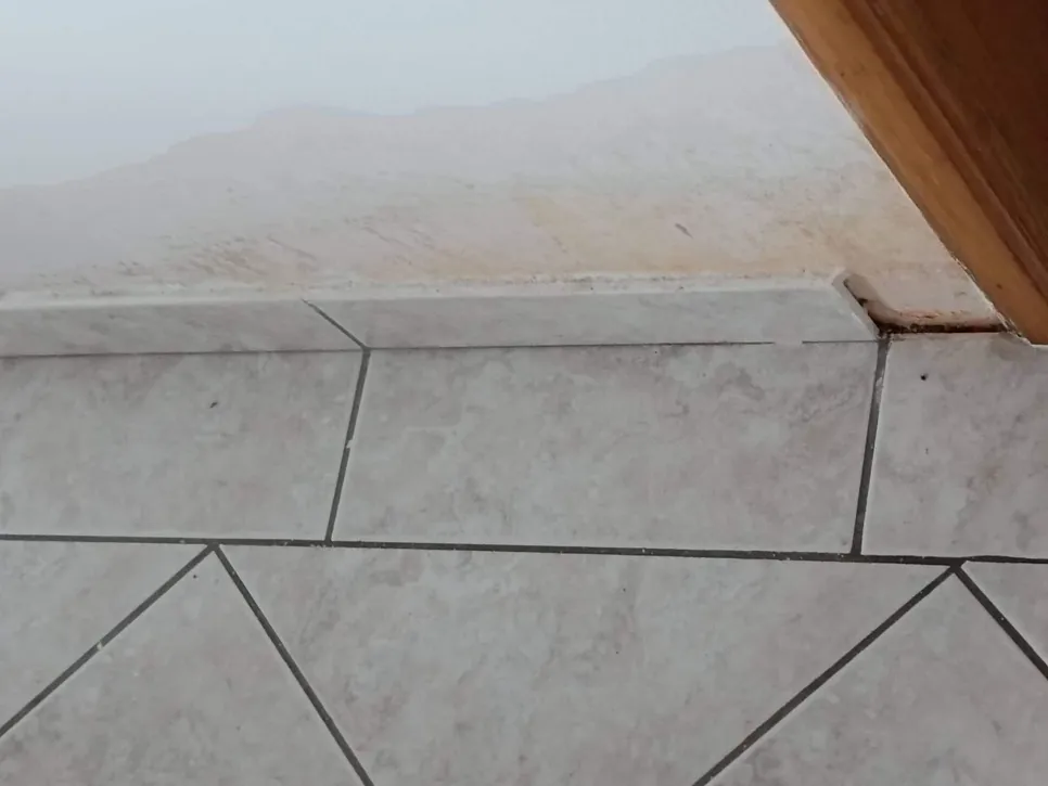 Oštećenje zida zbog vode u kutu Vidljive mrlje od vode u kutu zida i pločica, što ukazuje na oštećenje zbog vlage.